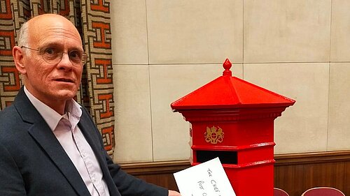 Tim posting a letter in a post box